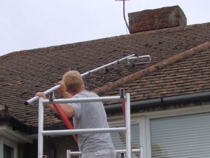 Manually scraping moss off a roof prior to soft washing -  All roof cleaning Services by Roof Repairs Belfast, Northern Ireland